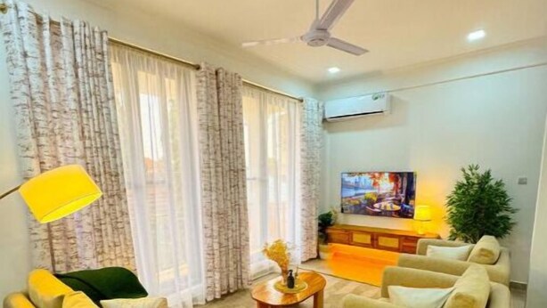 A living room with a sofa, armchairs, a coffee table, and a TV.