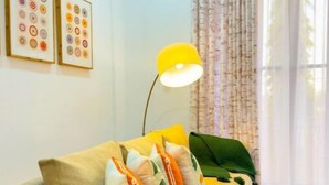 A living room with a sofa, pillows, a lamp, and two framed artworks on the wall.
