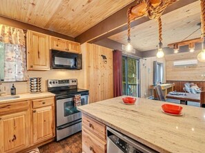 Una cocina con armarios de madera, microondas, horno y lavavajillas.