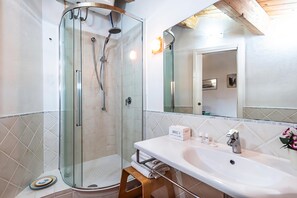 A modern bathroom with a glass-enclosed shower, a white sink, and a mirror above it.
