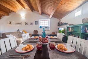 A dining area with a wooden ceiling, a table set for two with plates of food, glasses, and cutlery.