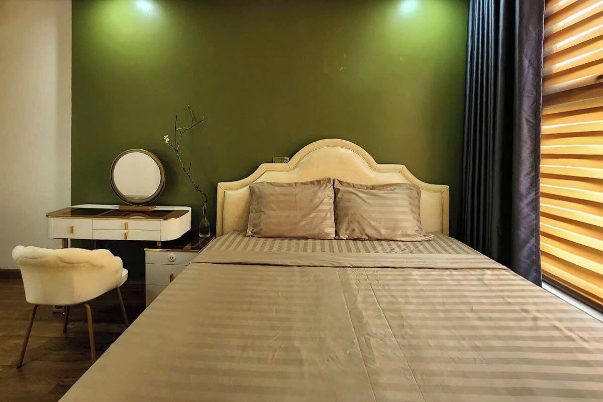 Una camera da letto con un letto, una toeletta con uno specchio, una sedia e una parete verde.