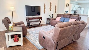A living room with a sofa, a TV, a lamp, and a small table with a vase.