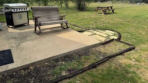 A patio area with a grill, a bench, and a picnic table.