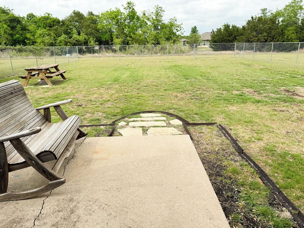 A concrete pathway leading to a picnic area with benches and a stone pattern.