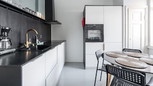 Una cocina moderna con encimera negra, electrodomésticos de acero inoxidable y una zona de comedor con individuales tejidos.