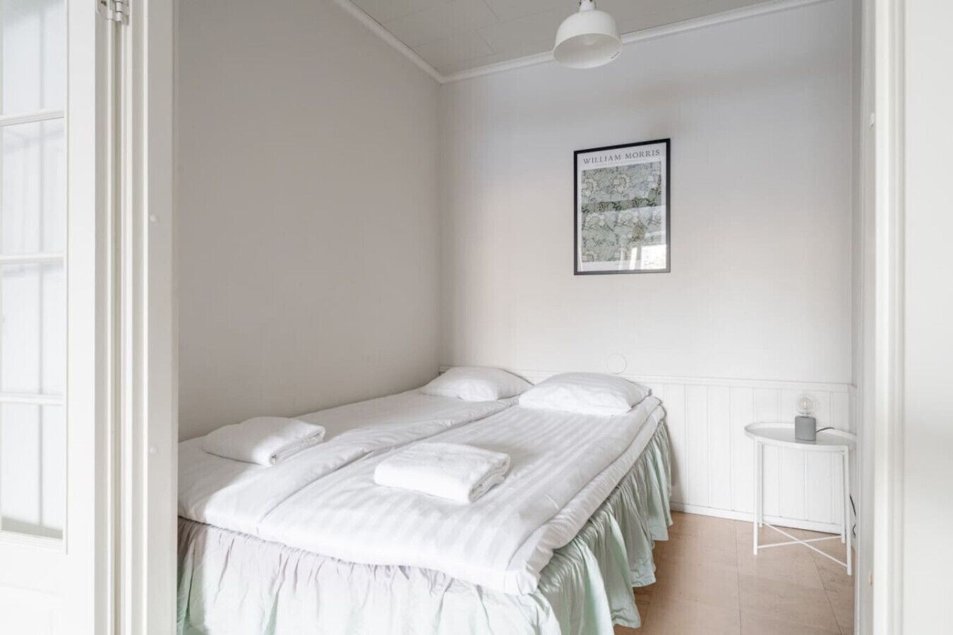 A bedroom with a bed, pillows, a bedside table, and a framed picture on the wall.