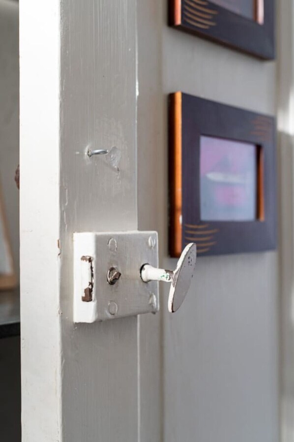 A door with a silver lock and a keyhole, a white door frame, and a framed picture on the wall behind it.