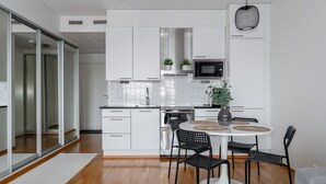 Een moderne keuken met witte kasten, een magnetron, en een eethoek met een ronde tafel en stoelen.