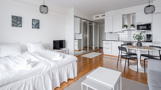 Een moderne hotelkamer met een groot bed, een televisie, een eethoek en een keuken.