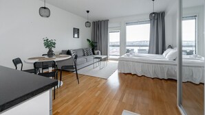 Een moderne, goed verlichte kamer met een eethoek, een bank, een bed en grote ramen met uitzicht.