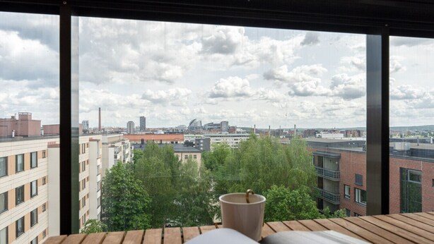 Ein modernes Zimmer mit großem Fenster und Blick auf die Stadt, einem Holztisch und einer Tasse.