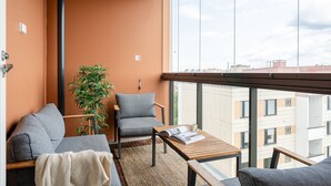 Ein modernes Apartment mit Sofa, Ohrensessel und einem kleinen Tisch mit Pflanze und Zeitschrift.