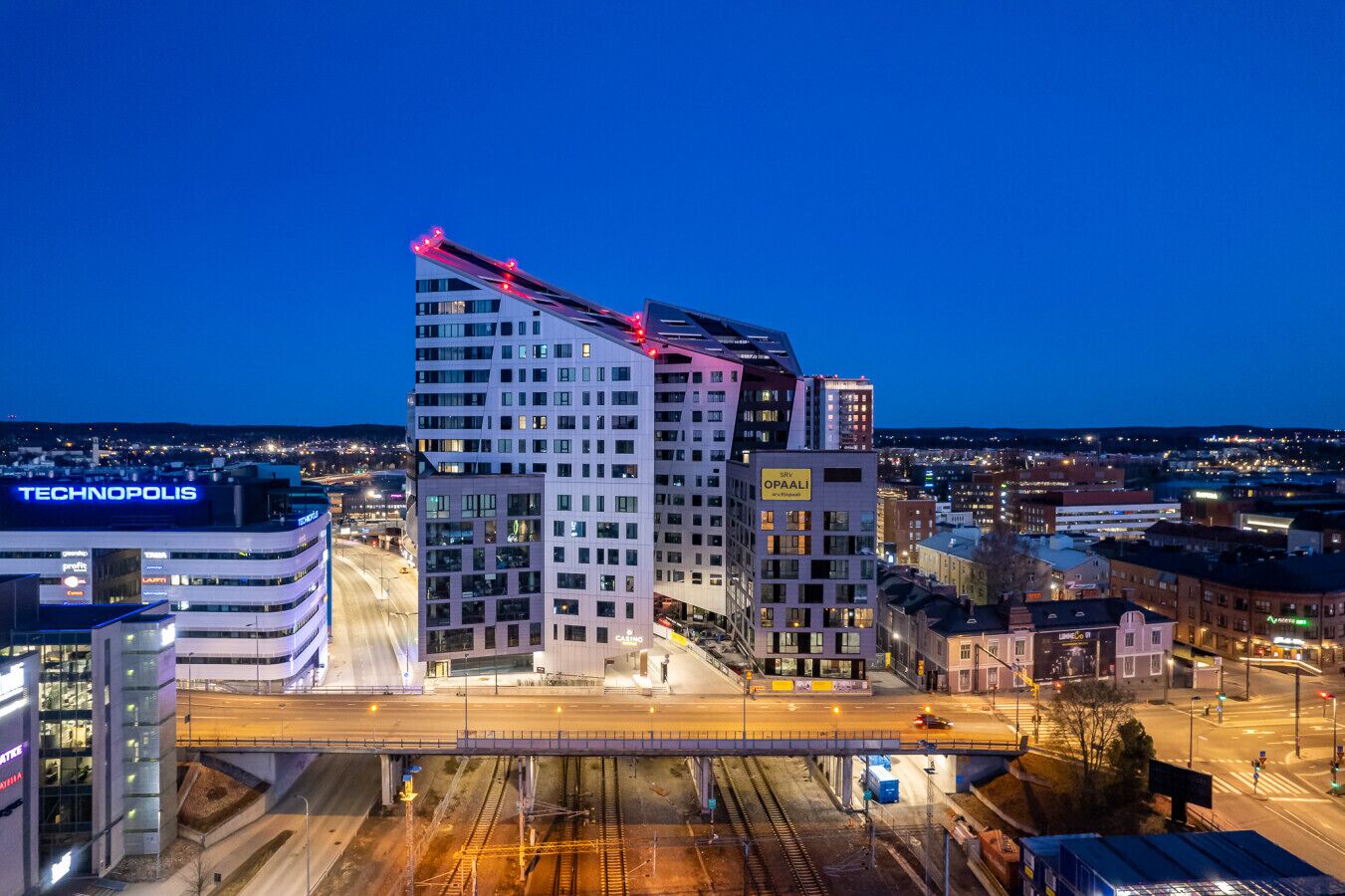 A modern high-rise building with multiple floors, a prominent crane on the roof, and a visible sign for 'TECHNOPOLIS'.