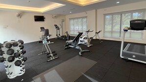 A gym with various exercise equipment, large windows, and a ceiling with recessed lighting. - Morib Prosper Resort by VP (Banting)
