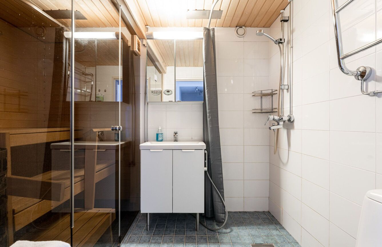 Un baño pequeño con cabina de ducha de vidrio, un lavamanos blanco y un espejo.