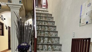 A staircase with stone steps and a wooden handrail, leading to an upper floor. - Jireh Antigua (Antigua Guatemala)