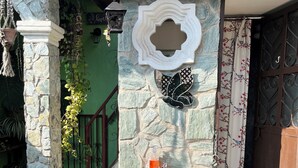 A stone-walled outdoor area with a white pedestal sink, a decorative wall piece, and a potted plant. - Jireh Antigua (Antigua Guatemala)