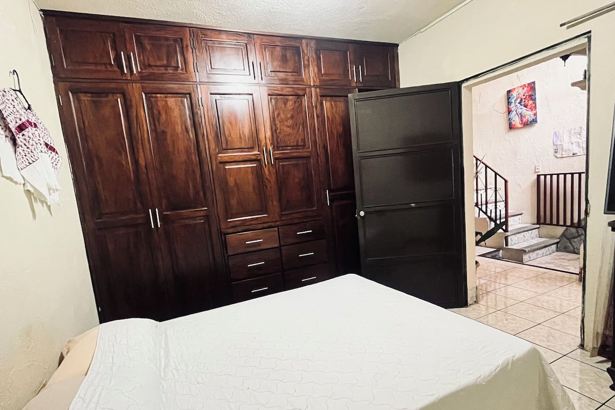 A bedroom with a bed, wooden wardrobe, and a staircase leading to an outdoor area.