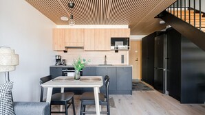Une cuisine moderne avec des meubles en bois, un four encastré et un réfrigérateur noir.
