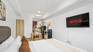 Une chambre d’hôtel moderne équipée d’un lit, d’un bureau et d’un téléviseur affichant le logo de Netflix.