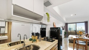 Une cuisine moderne dotée d’éviers en acier inoxydable, d’un réfrigérateur noir et d’un coin repas avec une table et des chaises en bois.