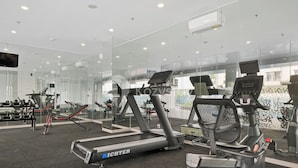 Une salle de sport moderne équipée de tapis de course, de vélos d’appartement et d’appareils de musculation.