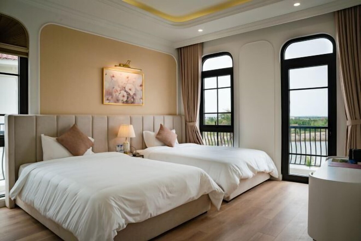 Habitació d'hotel amb dos llits, un finestral gran i un quadre a la paret.