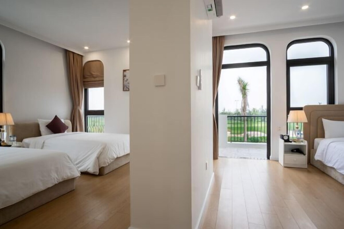 Habitació d'hotel amb dos llits, un balcó i grans finestres.