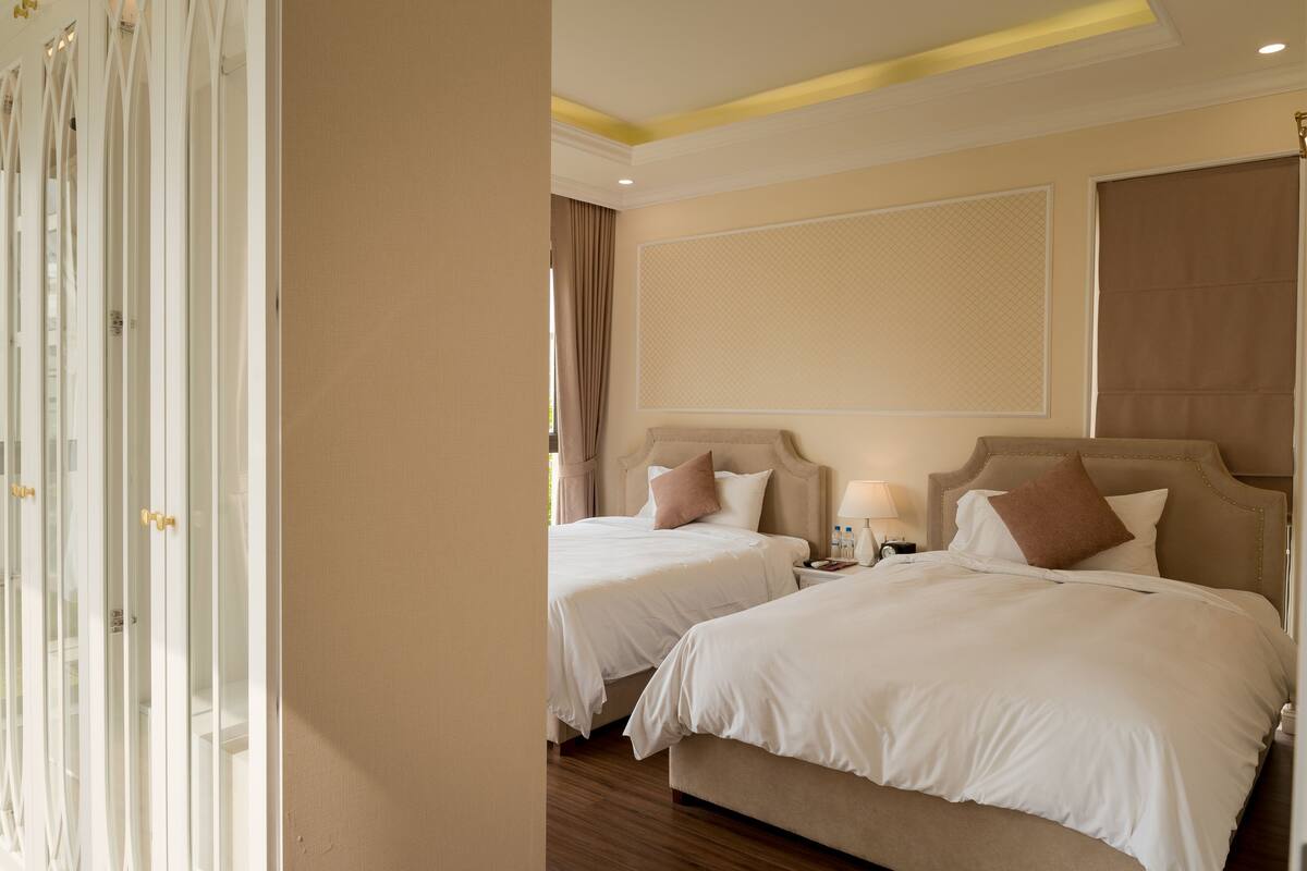 A hotel room with two beds, a large window with curtains, and a modern design.