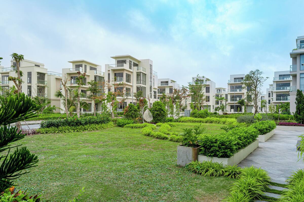 A modern residential complex with multiple buildings, green lawns, and well-maintained gardens.
