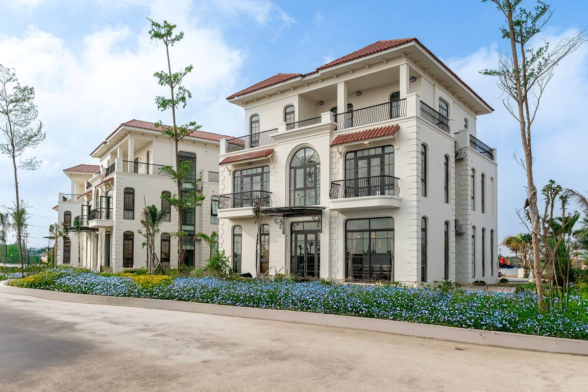 A large, two-story building with a symmetrical facade, multiple balconies, and large windows.