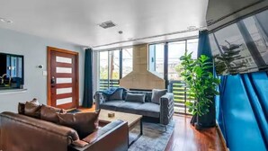 En moderne stue med sofa, sofabord og et stort vindue med udsigt til naturen.