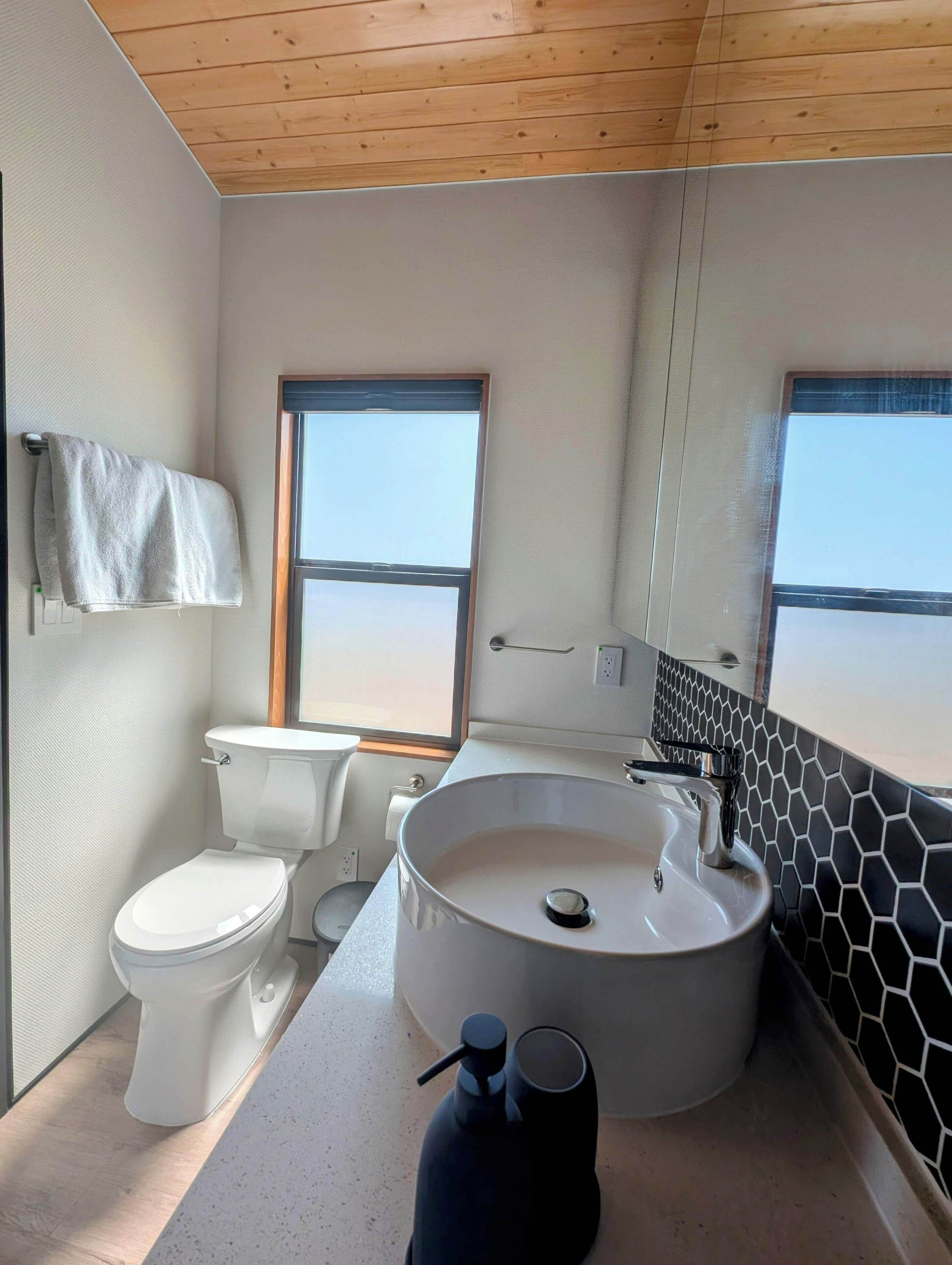 A modern bathroom with a toilet, sink, and large window.