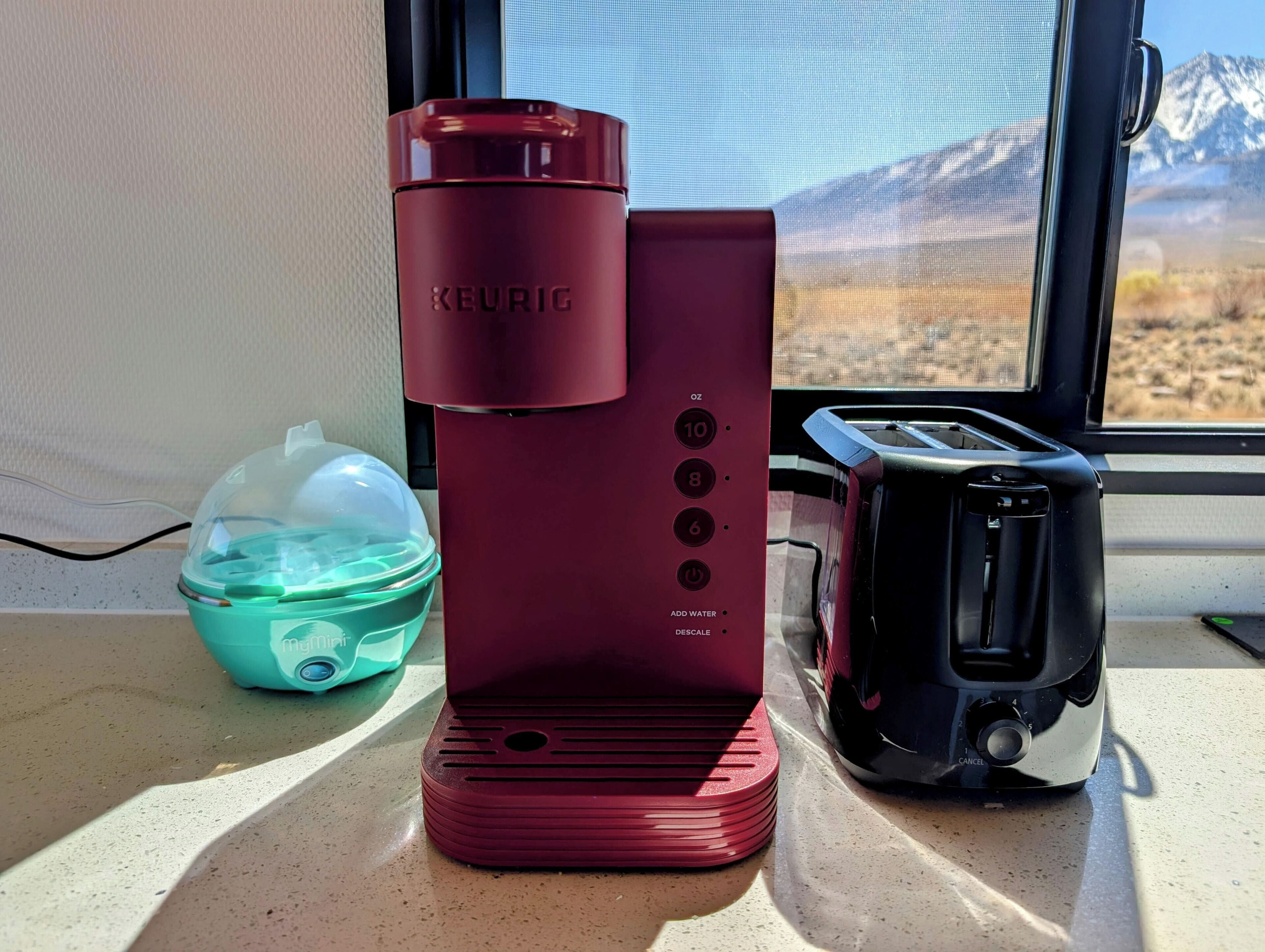 A Keurig coffee maker on a countertop next to a toaster and a water container.