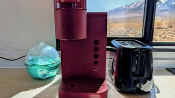 A Keurig coffee maker on a countertop next to a toaster and a water container.