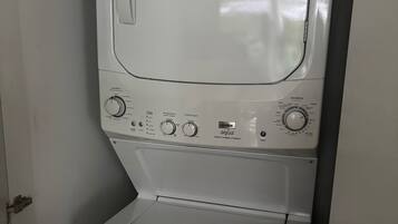 Une machine à laver à chargement frontal, dotée de boutons de commande et d’un distributeur de détergent.