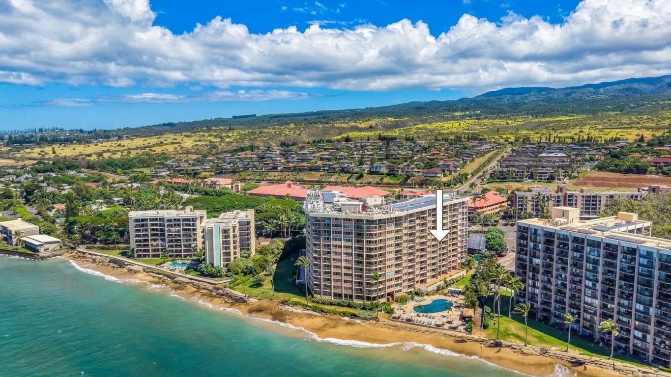 A coastal resort with multiple high-rise buildings, a beachfront, and a mountainous backdrop.