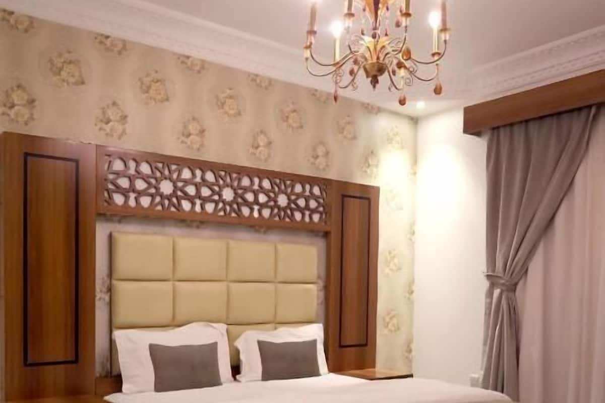 A bedroom with a large bed, wooden headboard, and a chandelier.