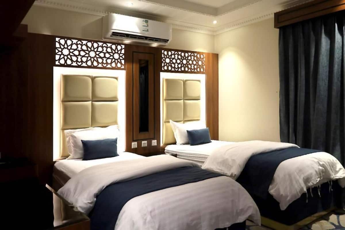 A hotel room with two beds, a large mirror, and a decorative partition.