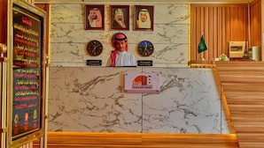 A hotel reception area with marble walls, clocks indicating London and New York time, and a sign with Arabic text. - rukn albahiat lilshuqaq almakhduma (Riyadh)