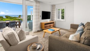 A modern living room with a flat-screen TV, comfortable seating, a wooden coffee table, and a view of the ocean. - Villa TreeHaus: Paradise Overlooking Grace Bay (Caicos Islands)