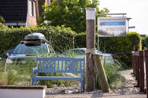 A bench, a Volkswagen car, and a sign for 'Ferienwohnungen Lütgens' with a website and phone number. - Apartment 'Möwe' with Shared Terrace, Shared Garden and Wi-Fi (Lübeck Travemünde)