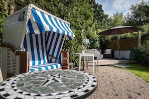 A patio area with a striped canopy, outdoor furniture, a mosaic table, and a hot tub. - Apartment 'Möwe' with Shared Terrace, Shared Garden and Wi-Fi (Lübeck Travemünde)