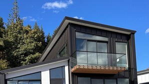 A modern two-story house with large windows, a wooden staircase, and a garage. - 1Queenstown - Stunning Lake and Mountain Views (Queenstown)