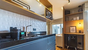 Cozinha moderna com bancada preta, eletrodomésticos embutidos e vista para a cidade.
