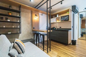 A modern kitchen with a microwave, bar stools, and a wooden countertop.