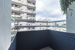 A balcony with a view of high-rise buildings and a cloudy sky.