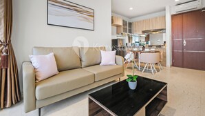 A modern living room with a beige sofa, a black coffee table, and a dining area with a white table and chairs.