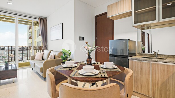 A modern living room with a dining table set for four, a sofa, and a kitchen area with a refrigerator and cabinets.